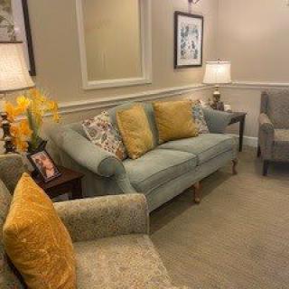 A cozy living room setup with a sofa, armchairs, and decorative elements like cushions and flowers.