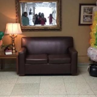 A cozy living room setting with a brown couch, a lamp on a side table, and festive balloons.