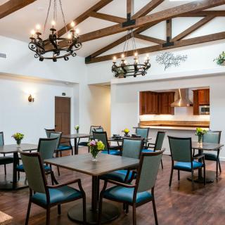 A well-lit dining area with wooden beams and elegant chandeliers.