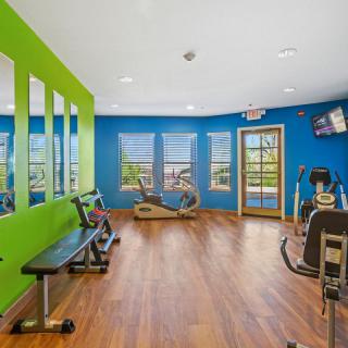 A brightly colored gym with various exercise equipment and wooden flooring.
