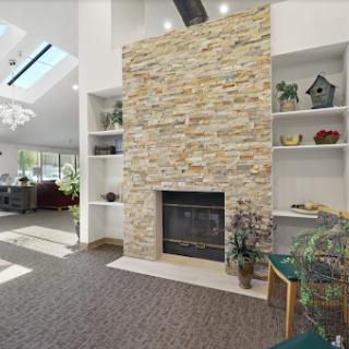 A stylish living room featuring a stone fireplace and built-in shelves, illuminated by natural light.