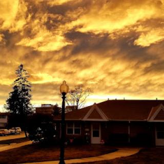 A stunning sunset casts a golden hue over the landscape, with clouds painting the sky.