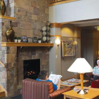 A cozy living room with a brick fireplace, comfortable seating, and warm lighting, where two people are relaxing.