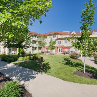 A scenic view of a residential building surrounded by a well-maintained garden with pathways and trees.