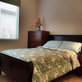 A cozy bedroom with a bed, dresser, and window.
