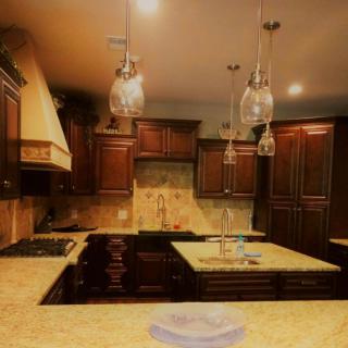 A modern kitchen with dark cabinets, pendant lighting, and a central island.