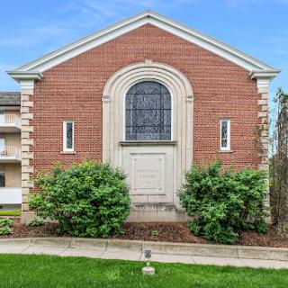 A charming brick building featuring an elegant entrance and well-maintained landscaping.