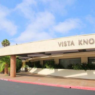 The entrance to Vista Knoll with clear skies and palm trees.