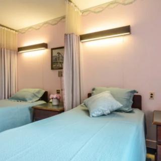 A cozy bedroom with a single bed, featuring pink walls and soft lighting.