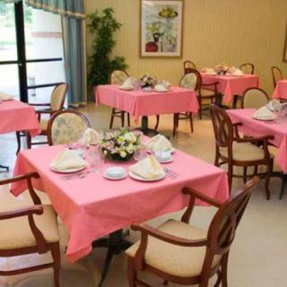 A cozy dining room with tables set in pink tablecloths, ready for guests.