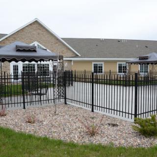 A view of a fenced patio area with a gazebo, adjacent to a residential building.