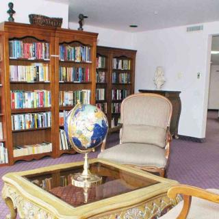 A cozy library room with bookshelves, a globe on a table, and a comfortable armchair.