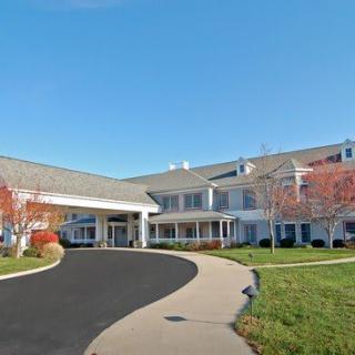A large building with a driveway and well-maintained landscaping under a clear blue sky.