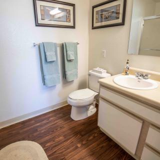 A well-kept bathroom featuring a toilet, sink, and neatly arranged towels on a wooden floor.