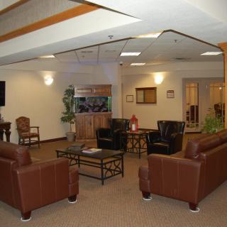 A comfortable lounge area with brown leather sofas and chairs, featuring a central coffee table and ambient lighting.