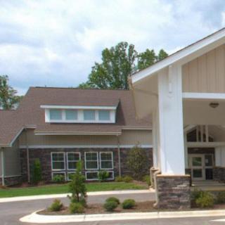 A building exterior with a covered entrance and landscaped surroundings on a clear day.