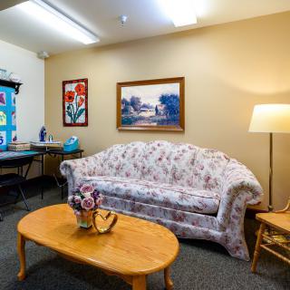 A cozy living room with a floral sofa, wooden coffee table, and artistic wall decorations.