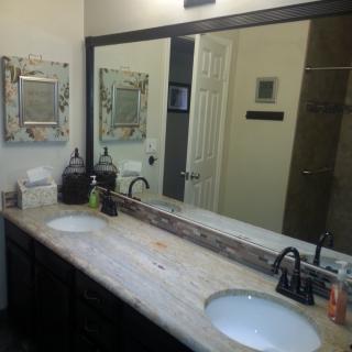 A modern bathroom with a large vanity mirror and double sinks.