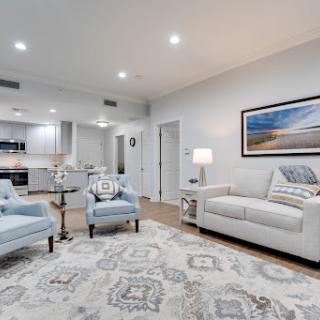A stylish modern living room featuring a white sofa, blue armchairs, and an elegant area rug.