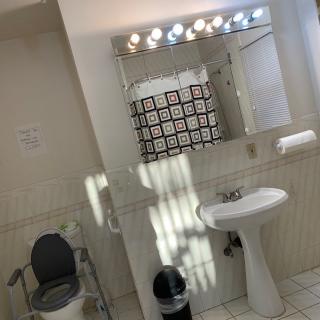 A well-lit bathroom with a sink, mirror, and toilet.