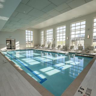 A serene indoor swimming pool bathed in natural light, featuring modern lounge seating.