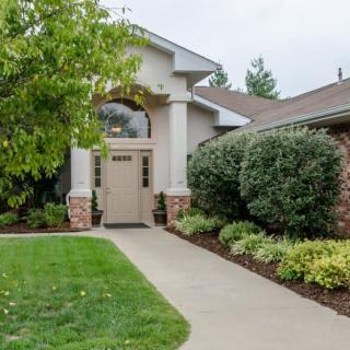 A welcoming house entrance with well-maintained landscaping and a paved pathway.