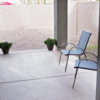 A minimalist patio with two chairs and potted plants.