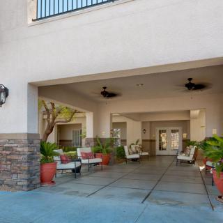 Covered entrance with outdoor seating and plants at a building.