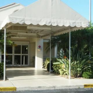 Entrance to a building with an awning and surrounding greenery.