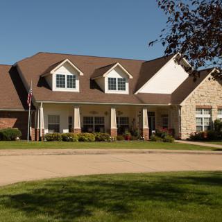 A large suburban house with a well-maintained lawn and clear blue sky.