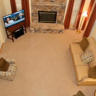 A cozy living room with a fireplace, sofas, and a television.