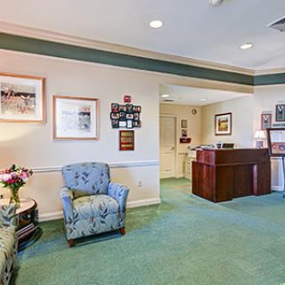 A well-decorated reception area featuring comfortable chairs, a desk, and artwork on the walls.