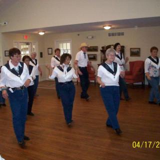 A group of people participating in a line dancing class indoors.