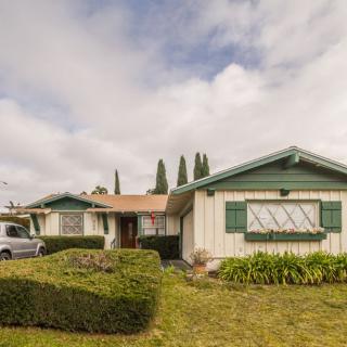 A suburban house with a well-maintained lawn and shrubs under a cloudy sky.