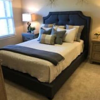 A cozy bedroom with a neatly made bed, decorative pillows, and soft lighting.