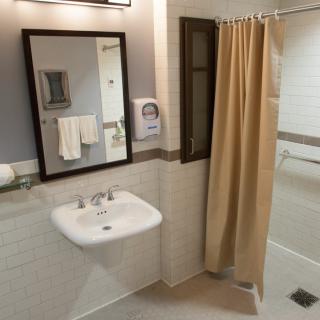 A clean and well-organized bathroom with a sink, mirror, and shower area.