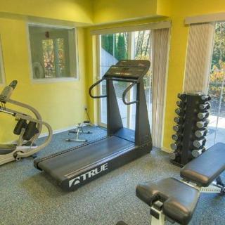A small indoor gym with a treadmill, weights, and other exercise equipment.