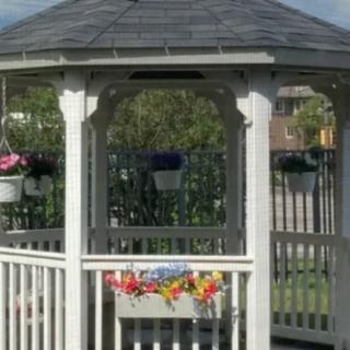 A quaint wooden gazebo adorned with colorful hanging flowers in a garden setting.