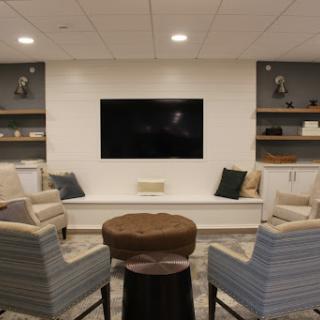 A modern living room setup featuring comfortable seating, a television, and stylish shelves.