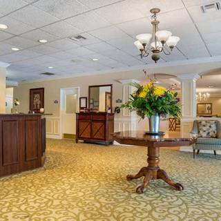 A cozy and elegant lobby featuring a reception desk, floral arrangement on a central table, and classic lighting.