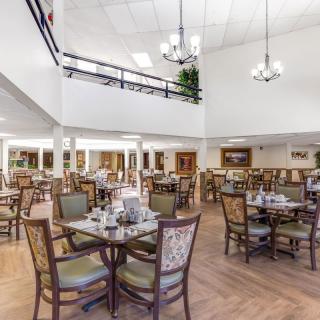 A spacious dining area with neatly arranged tables and chairs under elegant chandeliers.