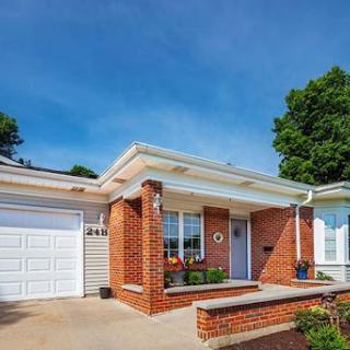 A welcoming brick house with a front porch and driveway under a clear blue sky.