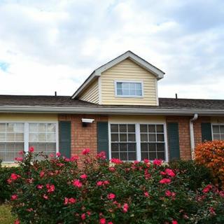A charming house with a brick facade and a front garden filled with blooming flowers.