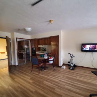 A cozy living area featuring a dining table, kitchen space, and a television.