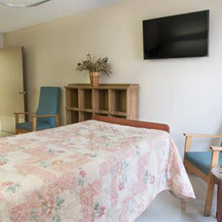 A well-furnished hospital room featuring a bed, a television, and comfortable seating.