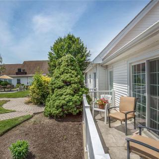 A cozy outdoor patio area with chairs overlooks a well-maintained garden and pathway.