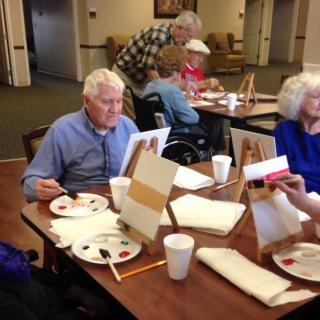 A group of elderly individuals participating in a painting activity at a senior center.