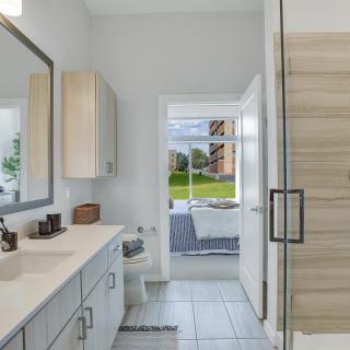 A modern bathroom with a spacious layout, featuring a sleek sink, large mirror, and a glass-enclosed shower.