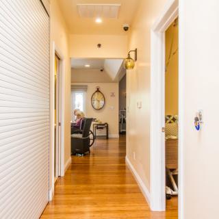 A bright hallway inside a home with wooden flooring and multiple doors leading to different rooms.