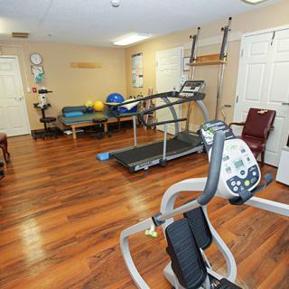 A well-equipped fitness room featuring a treadmill and various exercise machines on a wooden floor.